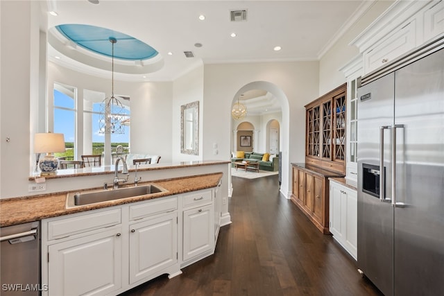 kitchen featuring dark wood-type flooring, white cabinetry, hanging light fixtures, and stainless steel appliances