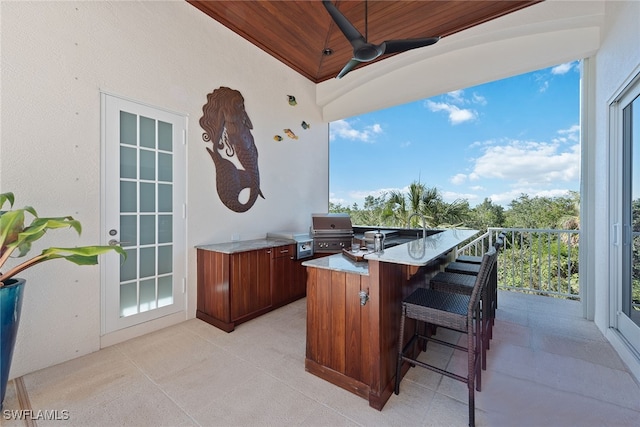 view of patio / terrace with a grill, exterior kitchen, ceiling fan, and a bar