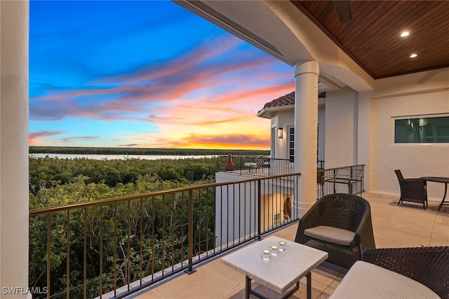 balcony at dusk featuring a water view