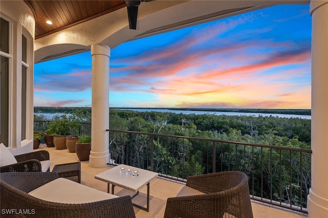 balcony at dusk featuring an outdoor living space, a water view, and ceiling fan