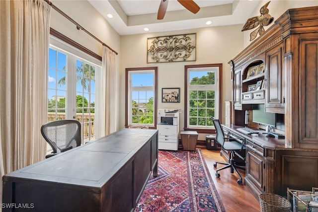 office space featuring ceiling fan, a raised ceiling, light hardwood / wood-style flooring, and french doors