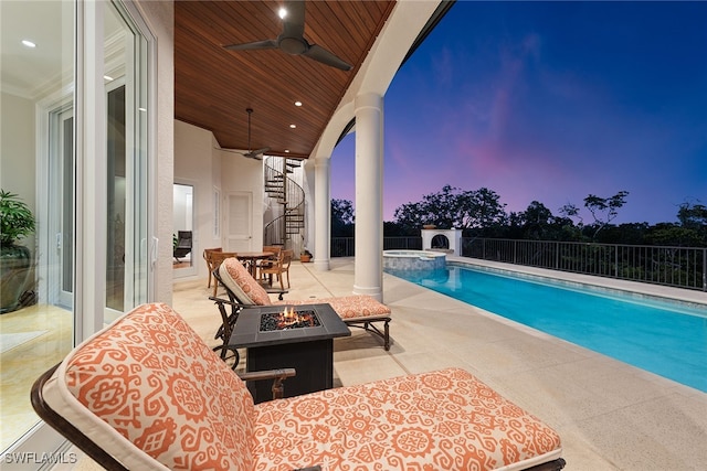 pool at dusk featuring a patio area, a fire pit, and ceiling fan