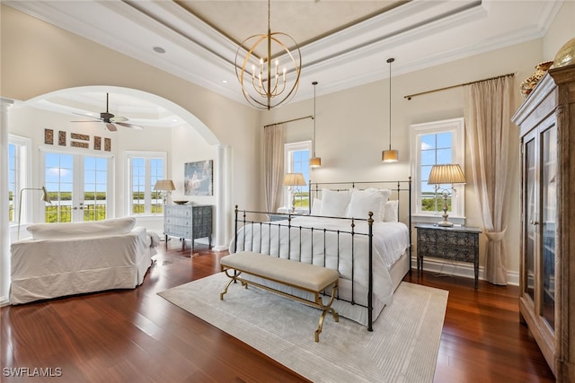 bedroom with french doors, crown molding, a raised ceiling, dark hardwood / wood-style flooring, and a chandelier