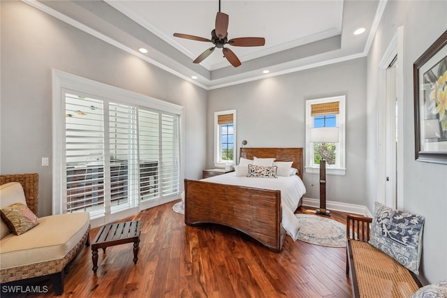 bedroom featuring hardwood / wood-style flooring, ceiling fan, ornamental molding, and a tray ceiling