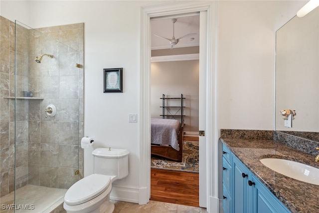 bathroom featuring tiled shower, toilet, hardwood / wood-style floors, vanity, and ceiling fan