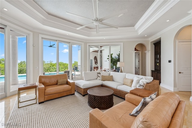 tiled living room featuring ornamental molding, ceiling fan, and a tray ceiling