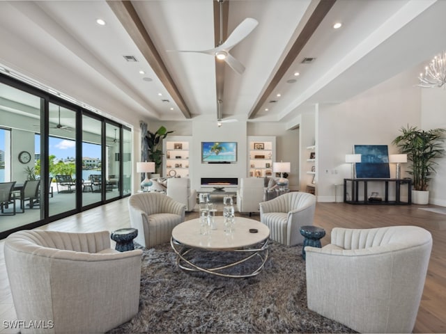 living room featuring ceiling fan with notable chandelier, beam ceiling, and hardwood / wood-style floors