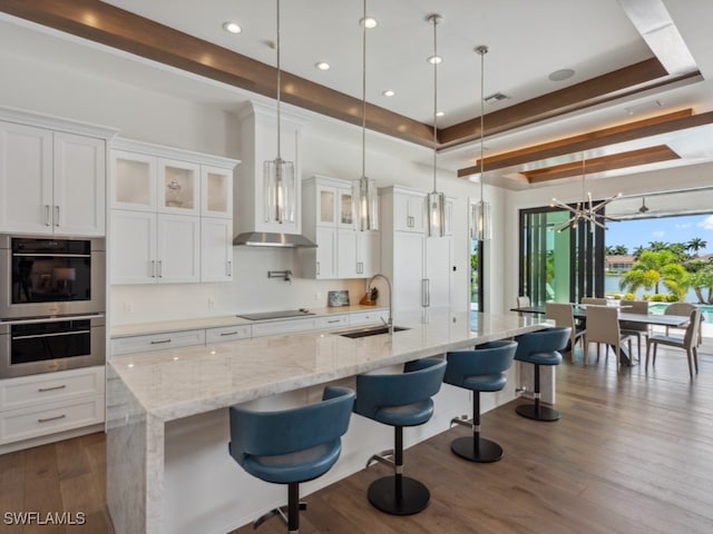 kitchen with a notable chandelier, a large island with sink, dark hardwood / wood-style floors, and decorative light fixtures