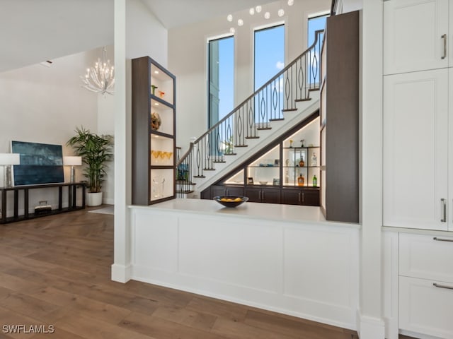 staircase with hardwood / wood-style floors and a notable chandelier