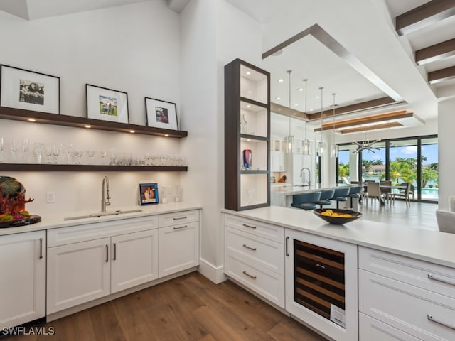 interior space featuring white cabinetry, beverage cooler, dark wood-type flooring, and sink