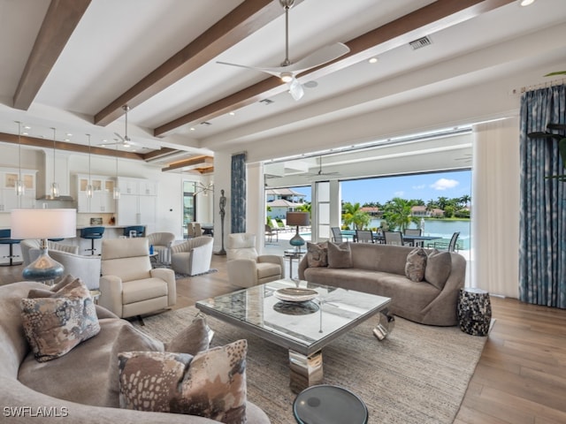 living room with a water view, light hardwood / wood-style floors, beamed ceiling, and ceiling fan