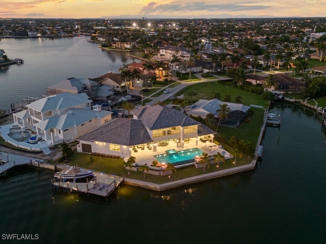 aerial view at dusk featuring a water view