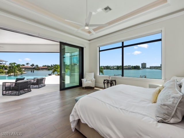 bedroom featuring multiple windows, a water view, ornamental molding, and hardwood / wood-style flooring