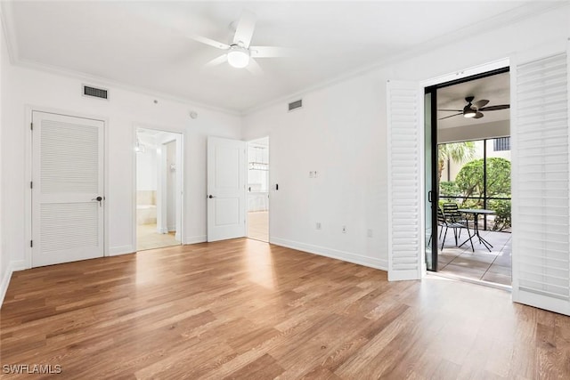 empty room with crown molding, baseboards, visible vents, and light wood-style floors