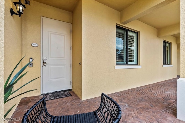 property entrance featuring visible vents and stucco siding