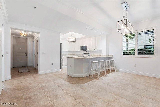 1035 Sandpiper St Unit F101, Naples, FL 34102 - kitchen with crown molding, a peninsula, light countertops, white cabinets, and appliances with stainless steel finishes