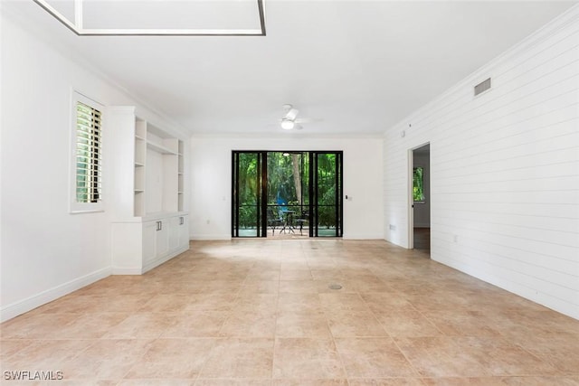 spare room with ceiling fan, visible vents, built in features, baseboards, and ornamental molding