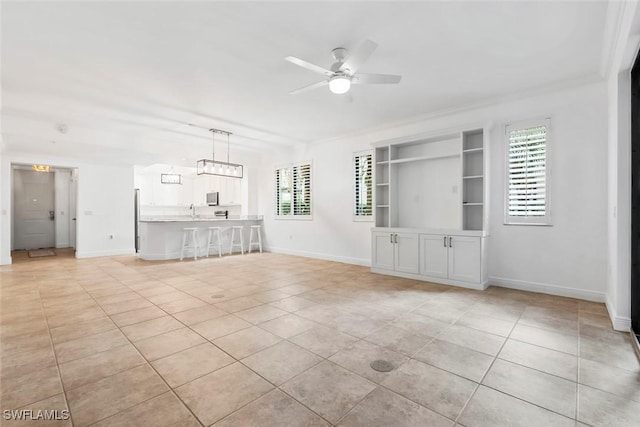 unfurnished living room with crown molding, sink, built in features, light tile patterned floors, and ceiling fan