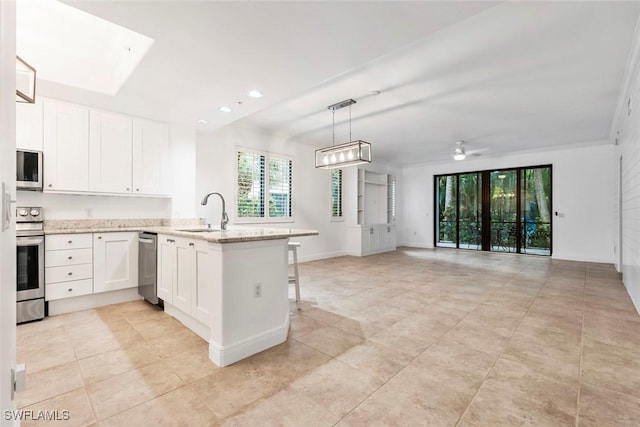 kitchen featuring electric range, white cabinets, a peninsula, light stone countertops, and a sink