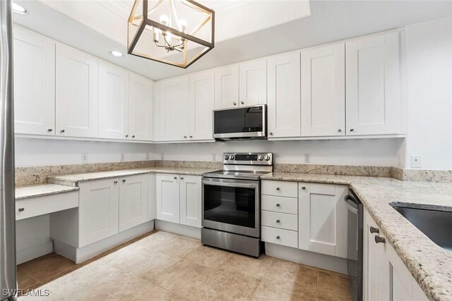 kitchen featuring light stone counters, appliances with stainless steel finishes, decorative light fixtures, and white cabinets