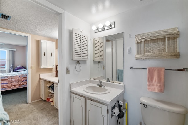 bathroom with a textured ceiling, vanity, and toilet