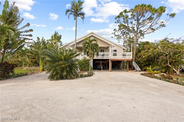 10610 Habitat Trl, Bokeelia, FL 33922 - raised beach house featuring a carport, dirt driveway, stairs, and a porch