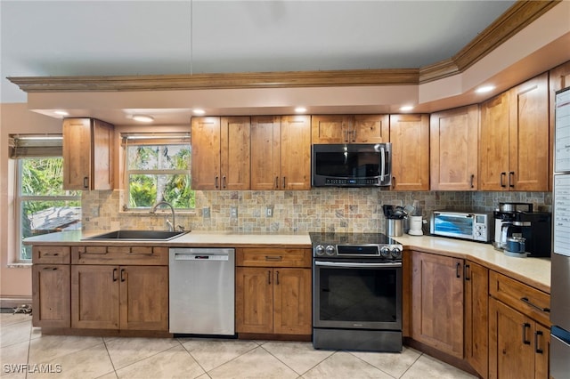 kitchen with decorative backsplash, ornamental molding, sink, and appliances with stainless steel finishes