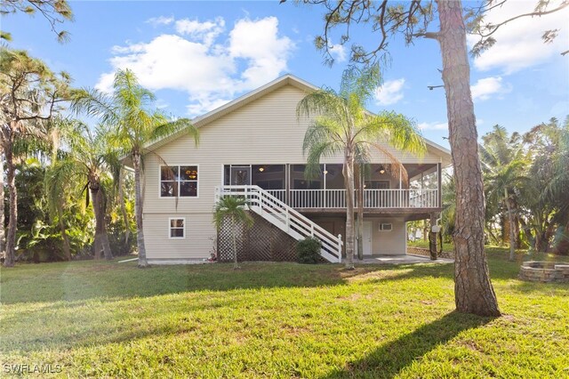 rear view of house with a lawn, a sunroom, and a deck