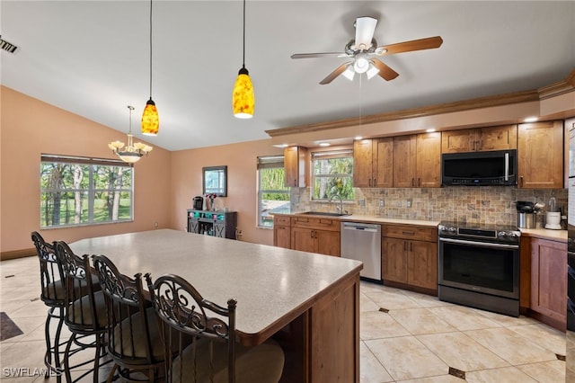 kitchen featuring a kitchen breakfast bar, tasteful backsplash, stainless steel appliances, sink, and decorative light fixtures