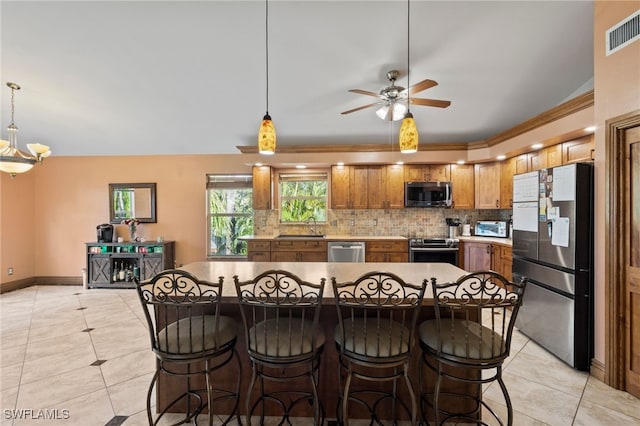 kitchen featuring backsplash, light tile patterned floors, stainless steel appliances, and hanging light fixtures