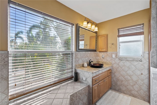 bathroom with a wealth of natural light, tile patterned flooring, vanity, and tile walls