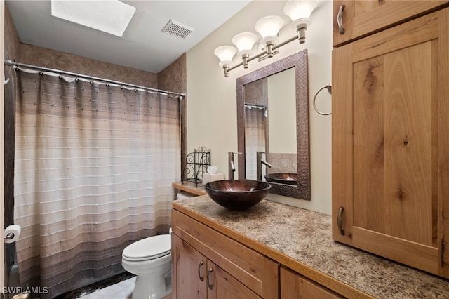 bathroom featuring a skylight, vanity, and toilet