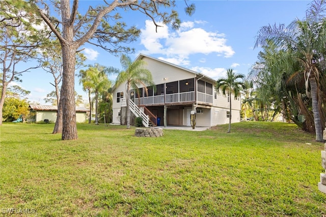 rear view of house featuring a sunroom and a lawn