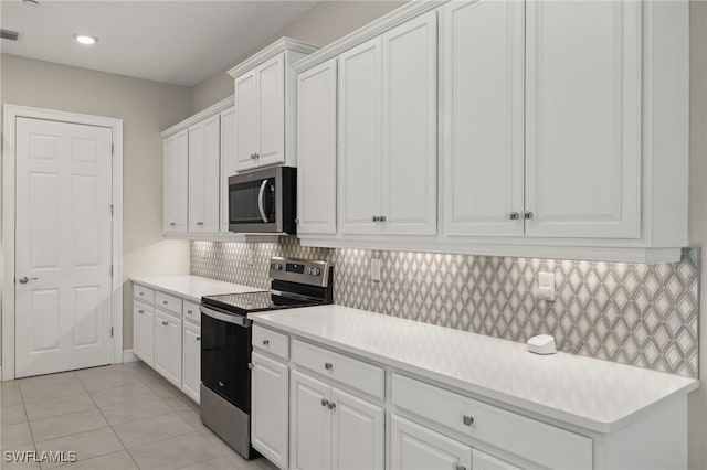 kitchen with white cabinets, light tile patterned floors, appliances with stainless steel finishes, and tasteful backsplash