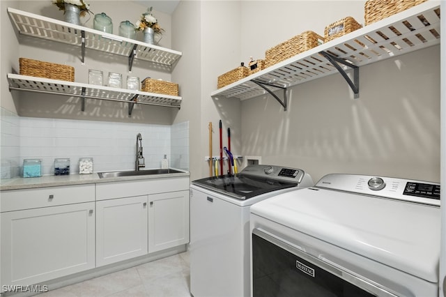 washroom featuring washing machine and clothes dryer, cabinets, light tile patterned floors, and sink