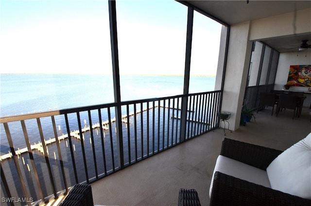 balcony with a view of the beach, a water view, and ceiling fan