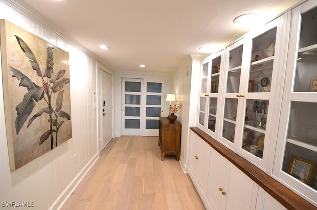 hall with light hardwood / wood-style flooring and crown molding