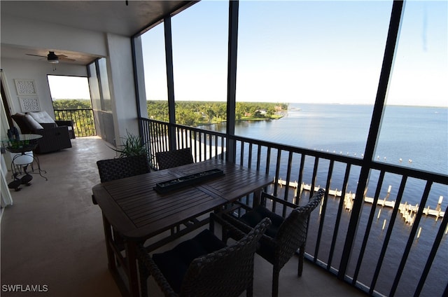 sunroom featuring ceiling fan and a water view