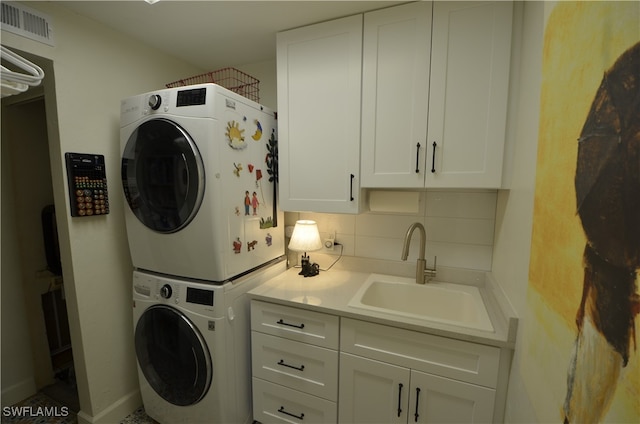 laundry room with cabinets, stacked washer / drying machine, and sink