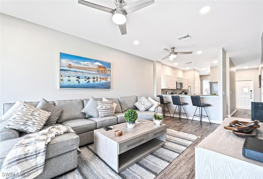 living room with dark hardwood / wood-style flooring, ceiling fan, and sink