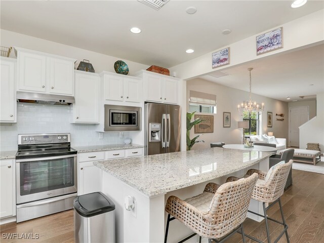 kitchen featuring a kitchen island, white cabinetry, stainless steel appliances, and a chandelier