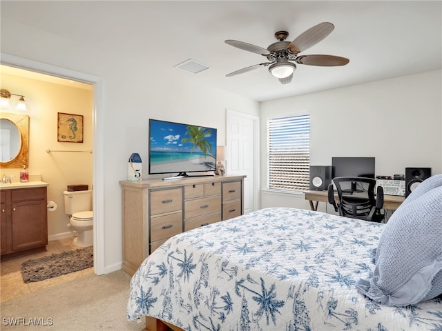 carpeted bedroom with ensuite bathroom and ceiling fan