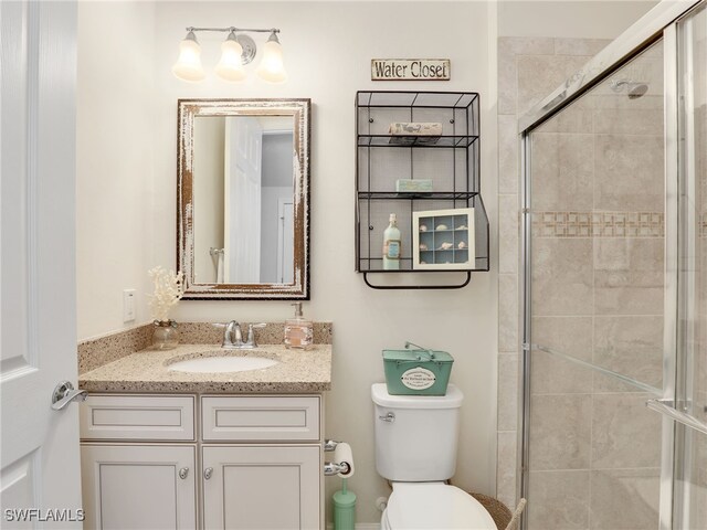 bathroom featuring vanity, toilet, and a shower with shower door