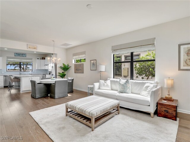 living room with light wood-type flooring and an inviting chandelier