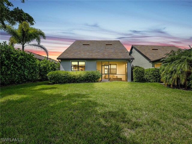 back house at dusk with a lawn