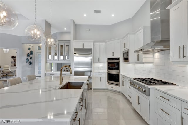 kitchen featuring hanging light fixtures, wall chimney range hood, decorative backsplash, and stainless steel appliances