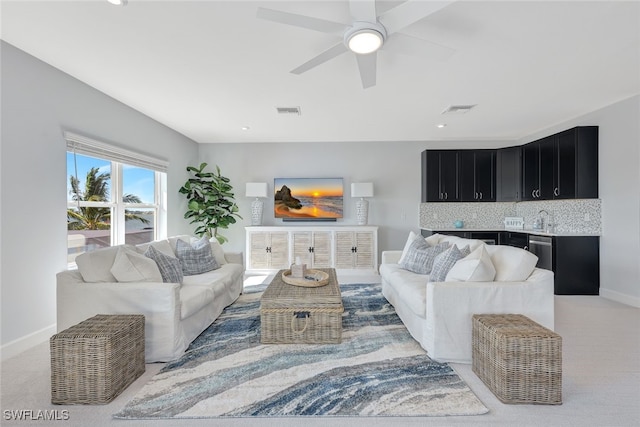 carpeted living room featuring ceiling fan and sink