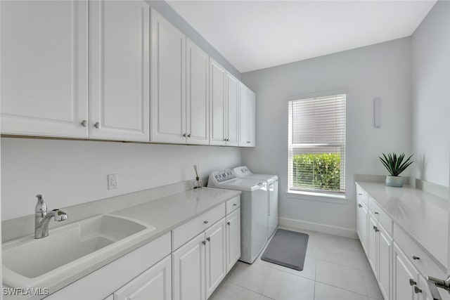 laundry area with cabinets, separate washer and dryer, light tile patterned floors, and sink