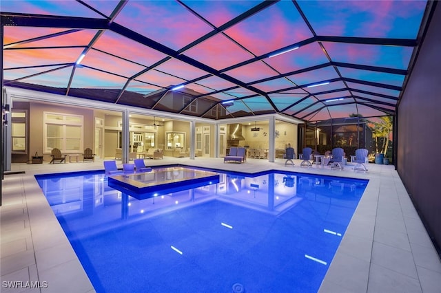 pool at dusk featuring ceiling fan, a lanai, an in ground hot tub, and a patio area