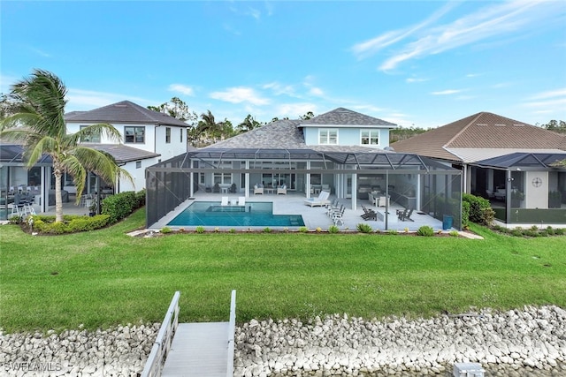 rear view of property with a patio area, glass enclosure, and a yard